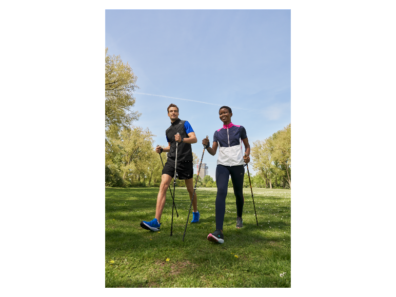 Twee mensen lopen in een park met nordic walking stokken.