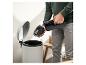 Homme vidant un aspirateur à main dans une poubelle.