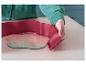 Une personne assemble un moule de cuisson en silicone rouge avec une base en verre.