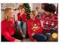 Famille souriante en pulls de Noël, avec un sapin de Noël en arrière-plan.