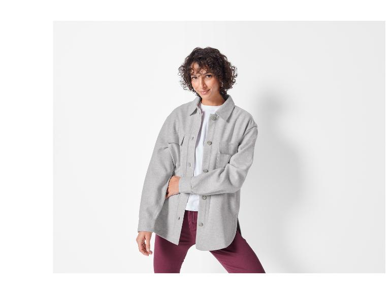Une femme porte une chemise-veste grise sur un t-shirt blanc.