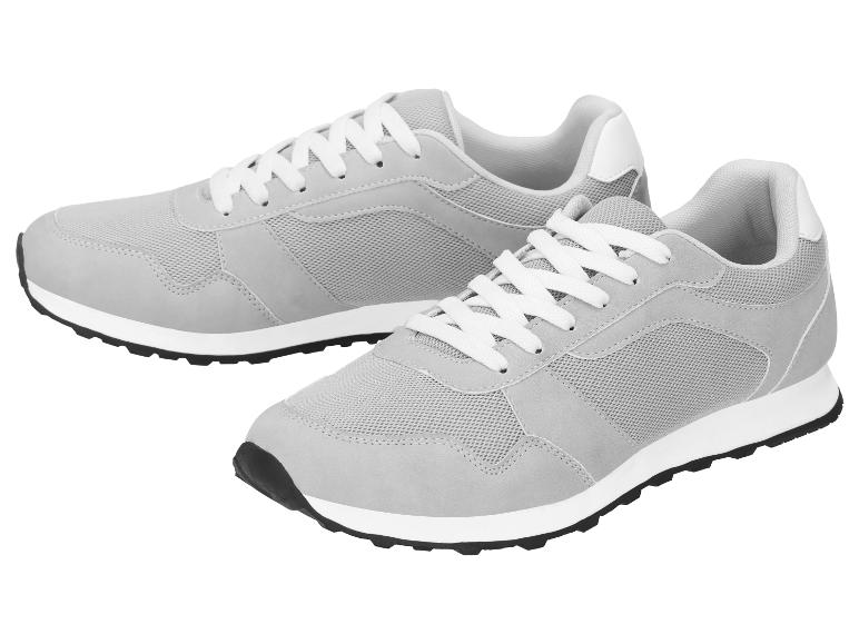 Grijze sneakers met witte veters en zwarte zolen.