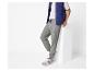 Een man in een blauw vest en grijze joggingbroek met sneakers.