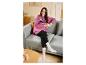 Femme en sweat à capuche Minnie Mouse et legging noir, tenant une tasse sur un canapé.