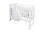Lit bébé en bois blanc avec gigoteuse et parure de lit à motifs étoiles et lune.