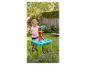 Fille jouant avec une table à sable et à eau dans le jardin.