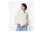 Vrouw in een wit overhemd en jeans.