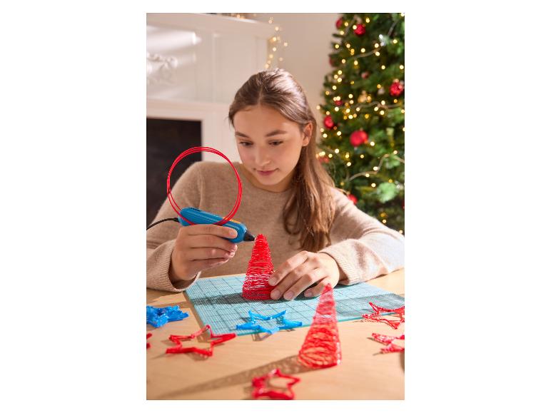 Une fille utilise un stylo 3D pour créer un sapin de Noël rouge.