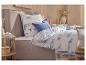 Wit beddengoed met blauw vissenpatroon en strepen, met blauwe kussens op een grijs bed.