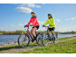 Een man en een vrouw fietsen op een verhard pad langs het water.