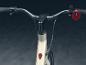 Het stuur van een witte elektrische fiets met een plusknop en een rode knop.