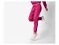 Persoon in de lucht draagt een fuchsia trainingspak en witte sneakers.
