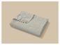 Couverture matelassée gris clair pliée sur un fond beige.