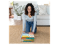 Une femme plie un tapis de jeu pour enfants aux motifs colorés et bohèmes.