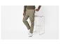 Homme en pull marron et pantalon cargo kaki, appuyé sur une chaise haute.