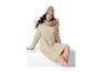 Vrouw in beige gebreide jurk, muts en sjaal, zittend.