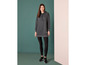 Een vrouw draagt een grijze hoodiejurk met leggings en sneakers.