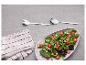 Verse salade met tomaten en croutons, naast saladebestek en een linnen servet.