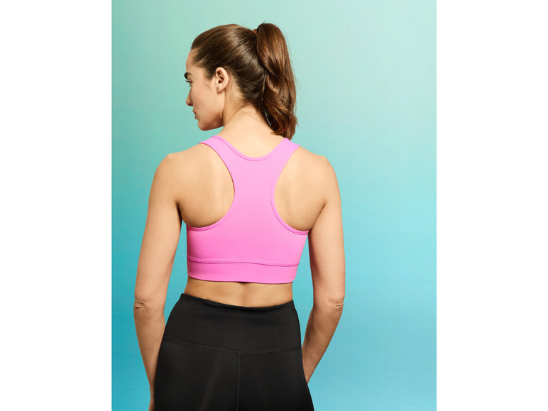 Een vrouw draagt een roze sportbeha en zwarte leggings.