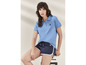 Vrouw draagt een blauwe polo en donkerblauwe shorts met witte strepen.