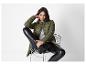 Une femme en doudoune verte et legging en cuir noir assise sur une chaise.