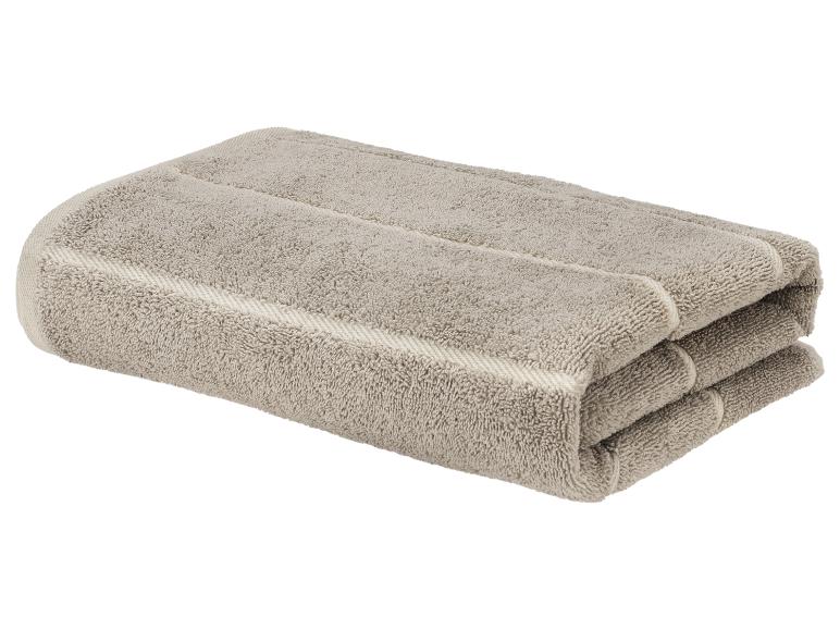 Serviette en coton beige pliée avec détails rayés.