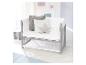 Lit bébé en bois gris avec literie blanche, oreillers et coussin en forme d'étoile.