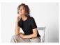 Une femme portant un t-shirt noir et un pantalon beige.