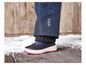 Een paar zwarte winterlaarzen met een rode zool, op een houten vloer met sneeuw.