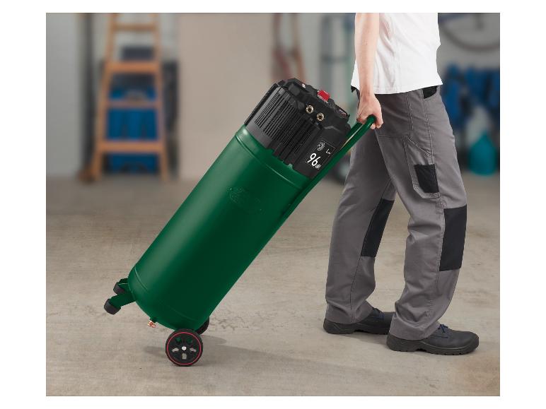 Een man duwt een groene compressor op wielen