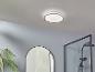 Een ronde plafondlamp in een badkamer met een spiegel en een douche.