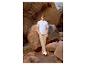 Homme en t-shirt bleu clair et pantalon beige debout parmi des formations rocheuses.