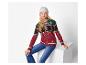 Une fille porte un pull de Noël bonhomme en pain d'épices et un jean, assise sur un cube blanc.