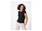 Vrouw in een zwart geribbeld T-shirt en beige broek, lachend.