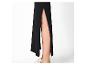 Jupe longue noire fendue, jambes visibles et chaussures de sport blanches.