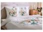 Bed met wit beddengoed met bloemenpatroon en bijpassende kussens.