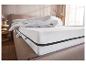 Wit matras met rits en donzig dekbed op een gestoffeerd bed.