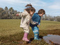 Deux enfants jouent dans la boue avec des bottes en caoutchouc.