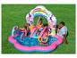 Enfants jouant dans un parc aquatique gonflable sur le thème des princesses avec toboggan et arroseurs sur l'herbe.