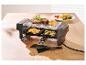 Appareil à raclette avec steak, pommes de terre et courgettes sur une table en bois.