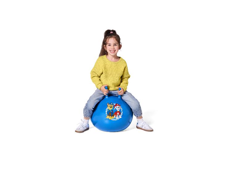 Petite fille souriante sur un ballon sauteur bleu Pat' Patrouille.