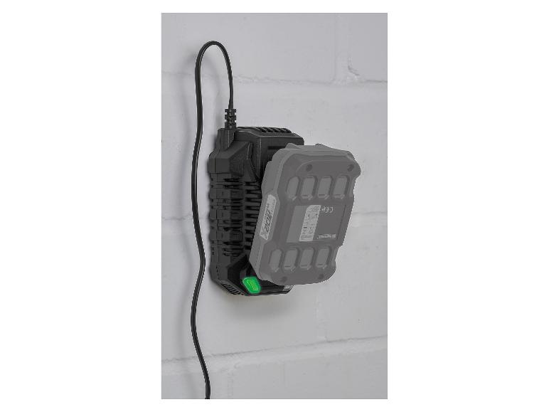 Zwarte oplader met een grijze batterij eraan, gemonteerd op een witte bakstenen muur.