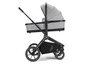 Een grijze kinderwagen met een zwarte beugel, grote wielen en een mandje.
