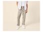 Homme en chemise rayée, t-shirt blanc et pantalon beige à cordon.