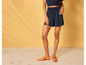 Vrouw draagt blauwe shorts en bruine sandalen.