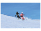 Twee skiërs dalen een besneeuwde helling af.