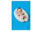 Een lachende baby in een beige romper op een gestippeld voedingskussen op een blauwe deken.