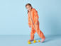 Un enfant portant un imperméable orange et des bottes roses marche avec des canards en caoutchouc.