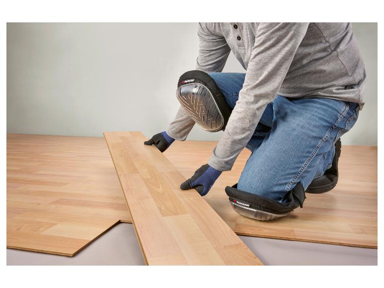 Man installeert laminaatvloer, draagt kniebeschermers en handschoenen.