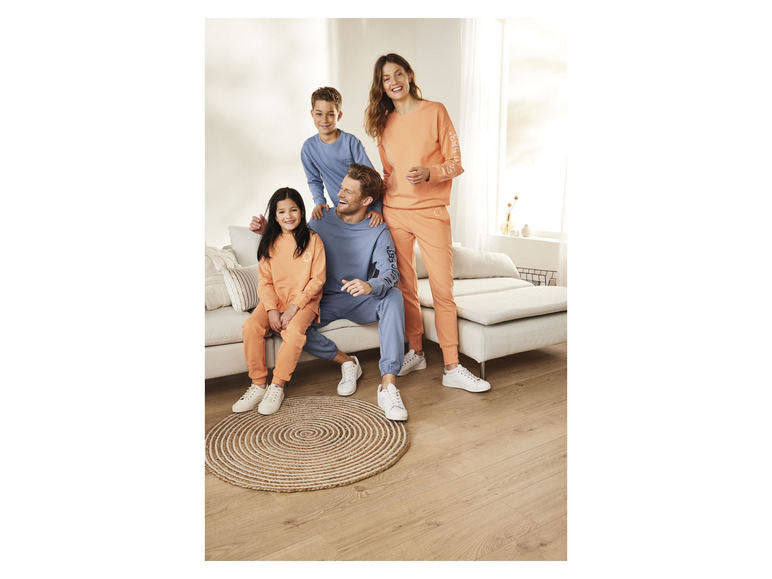 Une famille vêtue de vêtements décontractés, avec des sweat-shirts oranges et bleus et des baskets blanches.